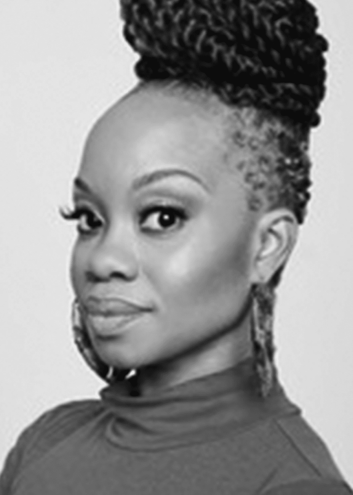 Camille A. Brown, a Black woman, with braided hair, poses for a portrait.
