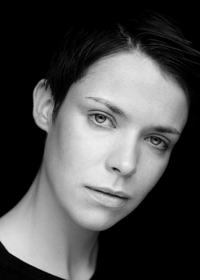 Black and white portrait of a woman with short hair, gazing intently at the camera.