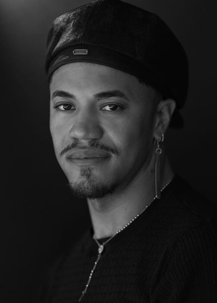 Black and white portrait of Carlos Falú wearing a beret and earrings, looking at the camera.