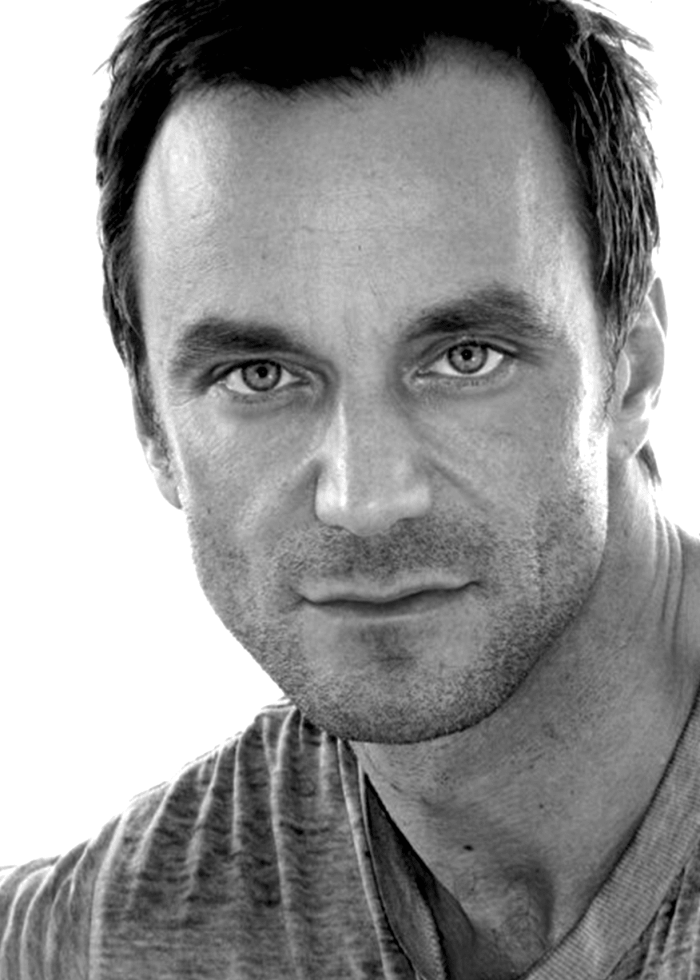 Jon David Casey headshot, looking directly at the camera in black and white.