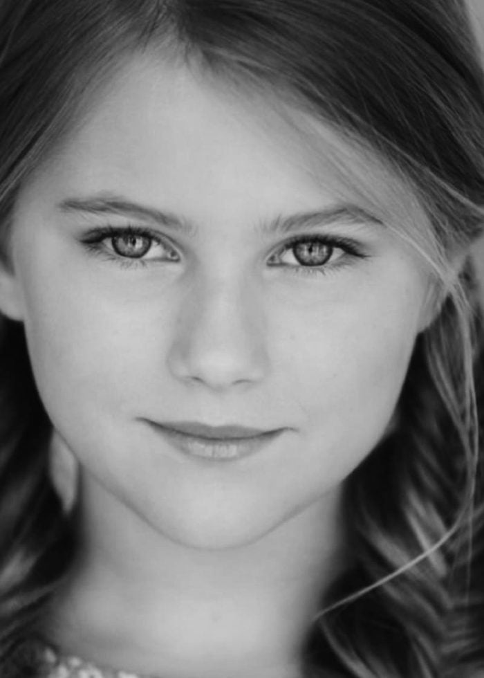 Close-up portrait of a young girl with blonde hair and a gentle smile.