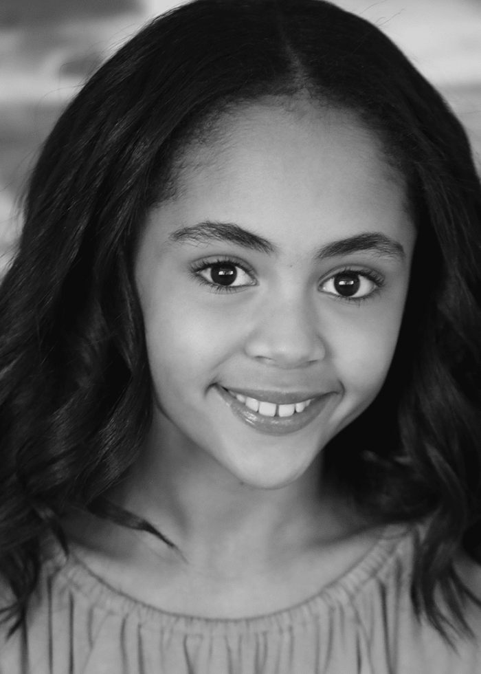 Smiling young girl with dark wavy hair, looking directly at the camera.