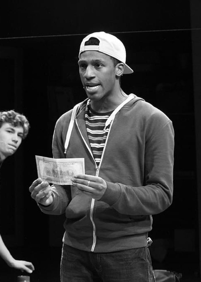 Actors in "Mr. Chickee's Funny Money" play on stage, one holding a bill, looking worried.
