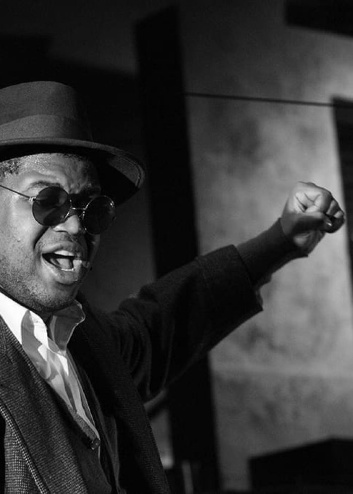 Actor in fedora and sunglasses performs in MR. CHICKEE'S FUNNY MONEY R&B musical.
