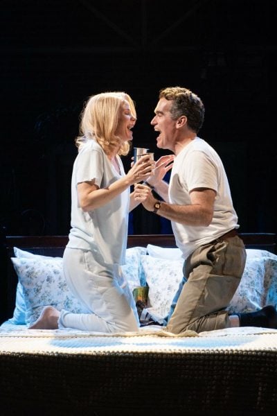 Actors in "Days of Wine and Roses" musical on stage, portraying an emotional scene on a bed.