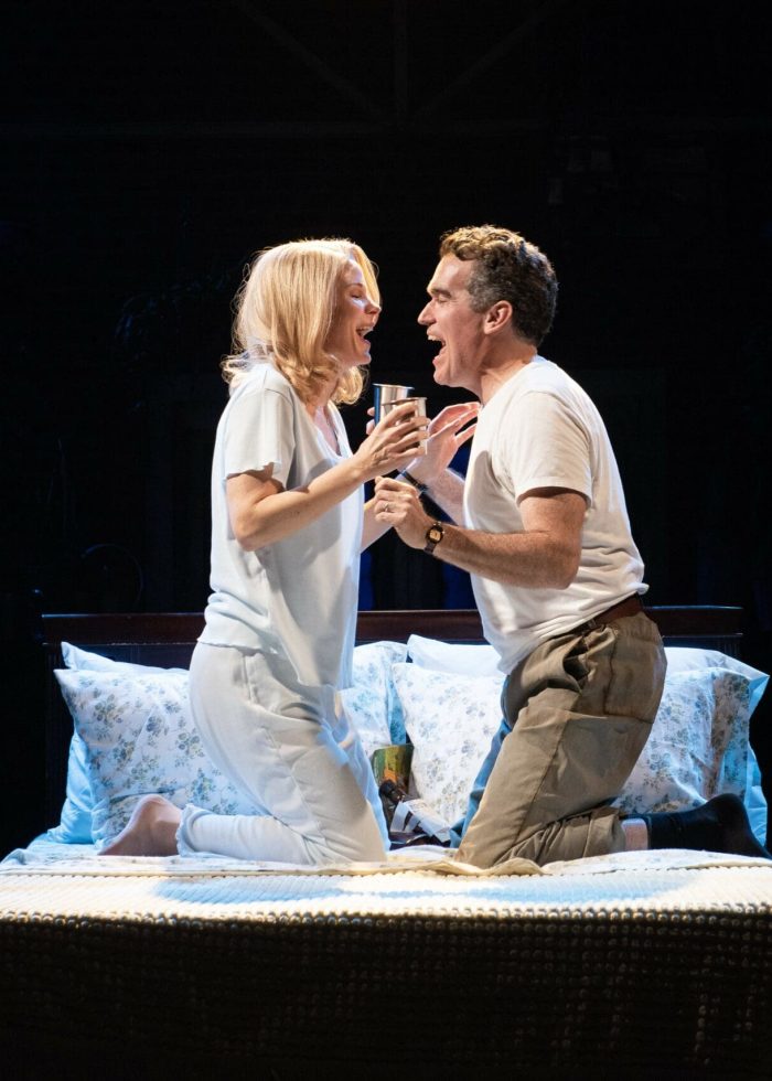 Actors in "Days of Wine and Roses" musical on stage, portraying an emotional scene on a bed.