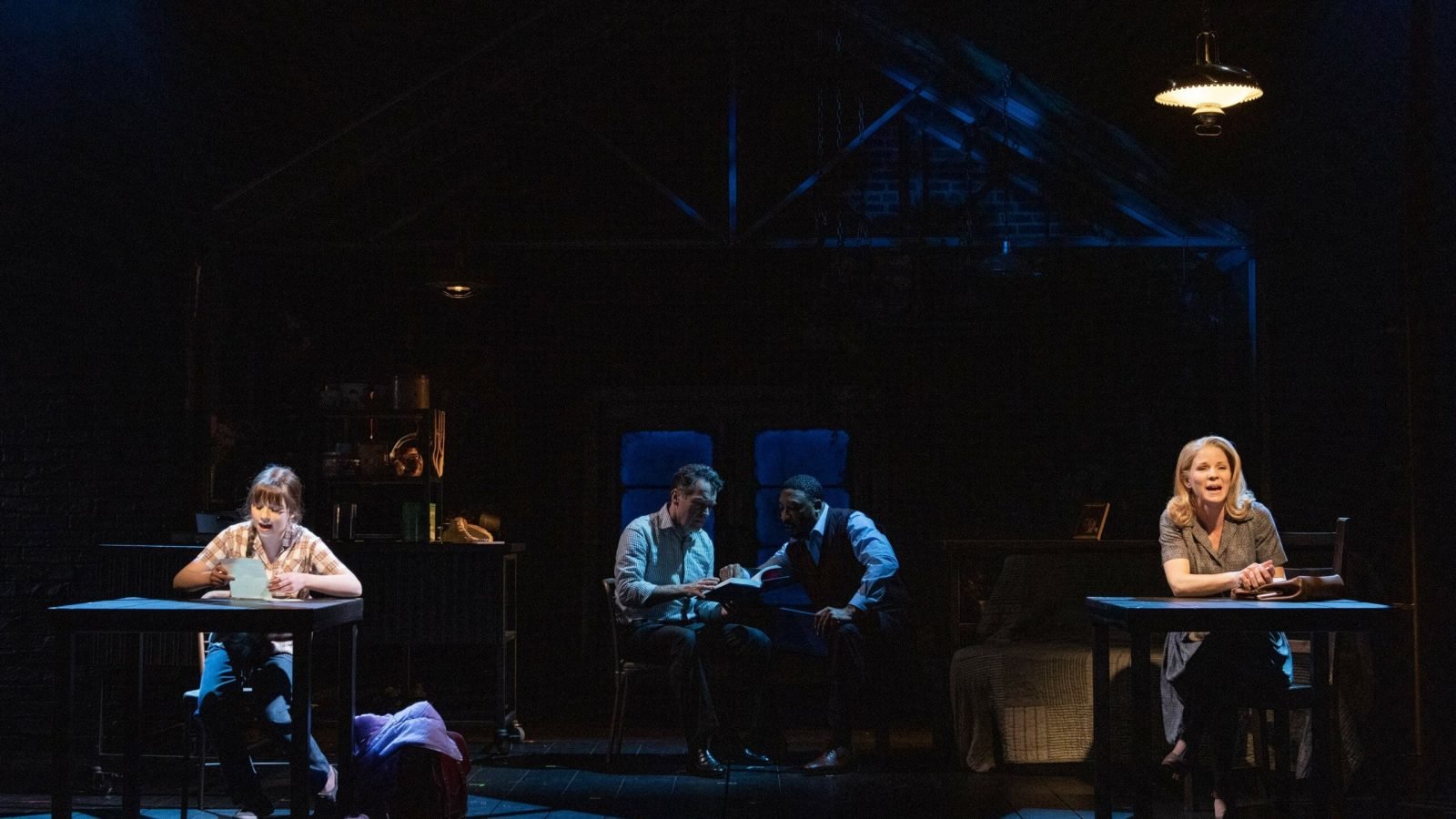 Four actors in a dimly lit theatrical scene, seated at individual tables, portraying a poignant moment from "Days of Wine and Roses.