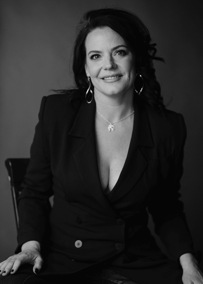 Danielle Skraastad, smiling in a black blazer, seated portrait.