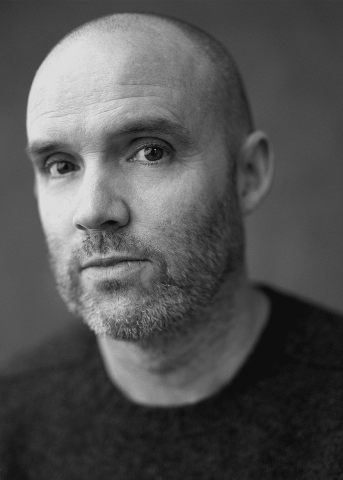 Close-up portrait of Danny Wolohan, a man with a shaved head and beard, looking directly at the camera.