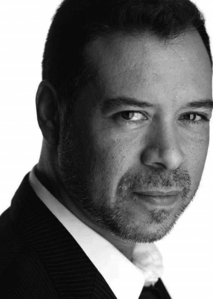 David Anzuelo looking at the camera, wearing a suit