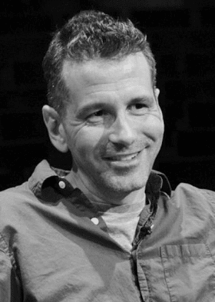 David Cromer smiling, wearing a button-down shirt, looking towards the viewer.