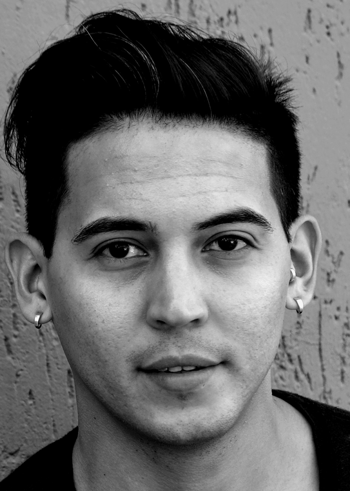 Close-up portrait of David Mendizábal, a young man with dark hair and hoop earrings.