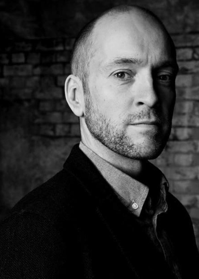 Derren Brown looking directly at the camera, in a black and white portrait.
