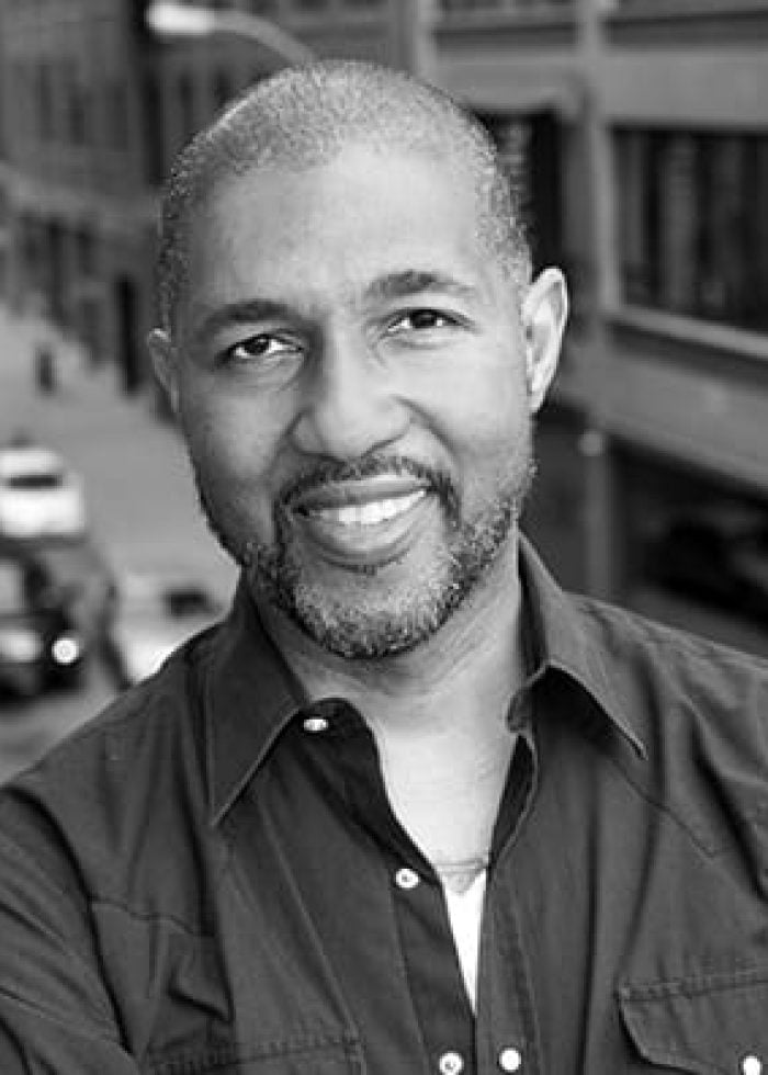 Portrait of Dion Graham smiling, with a city street in the background.