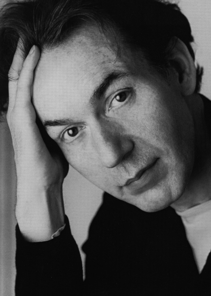 Close-up portrait of a man with dark hair, looking towards the camera.