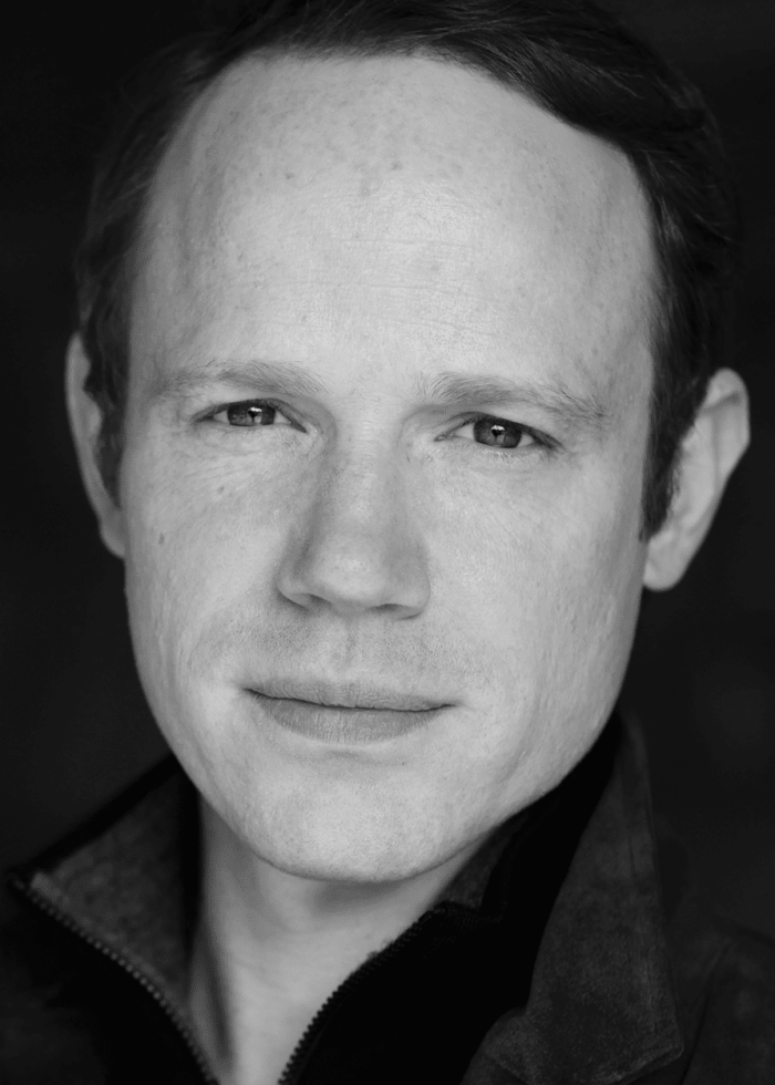 Actor Sean Dugan looking directly at the camera in a black and white headshot.