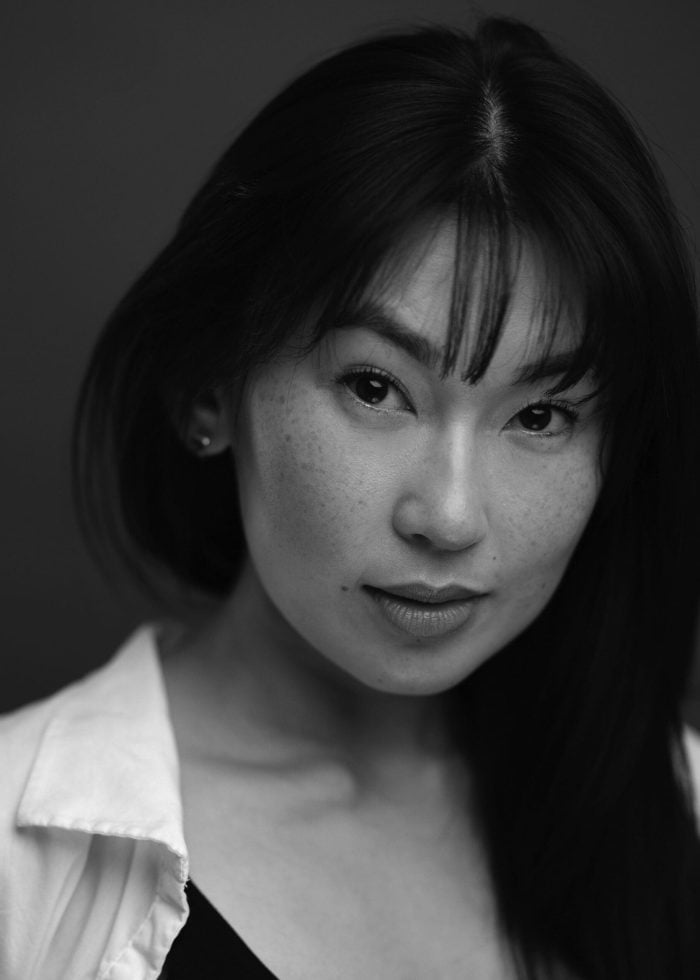 Close-up portrait of Lennox T. Duong, a woman with dark hair and freckles, looking at the camera.