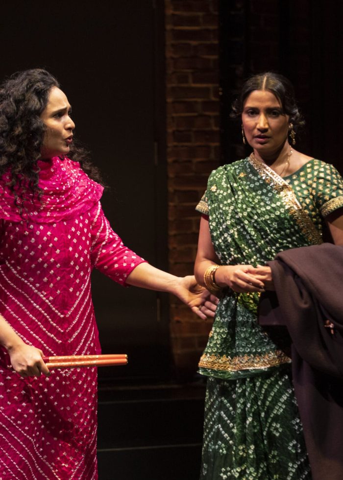 Two actresses in colorful traditional clothing perform on stage at the Atlantic Theater Company.