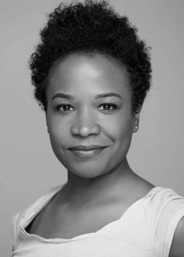 Eboni Booth, smiling, looking at the camera in black and white