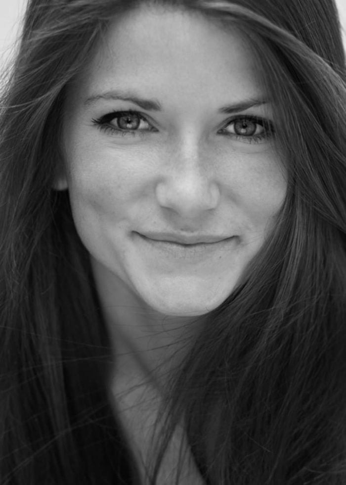 Close-up portrait of Emily Pendergast smiling with long brown hair.