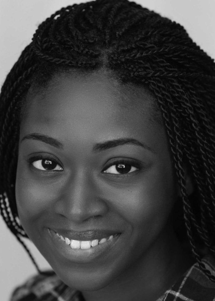 Close-up portrait of Emma Claye, smiling with braided hair