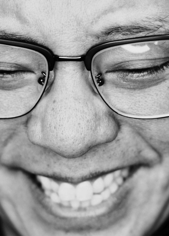 Close-up of a smiling person wearing glasses with eyes closed