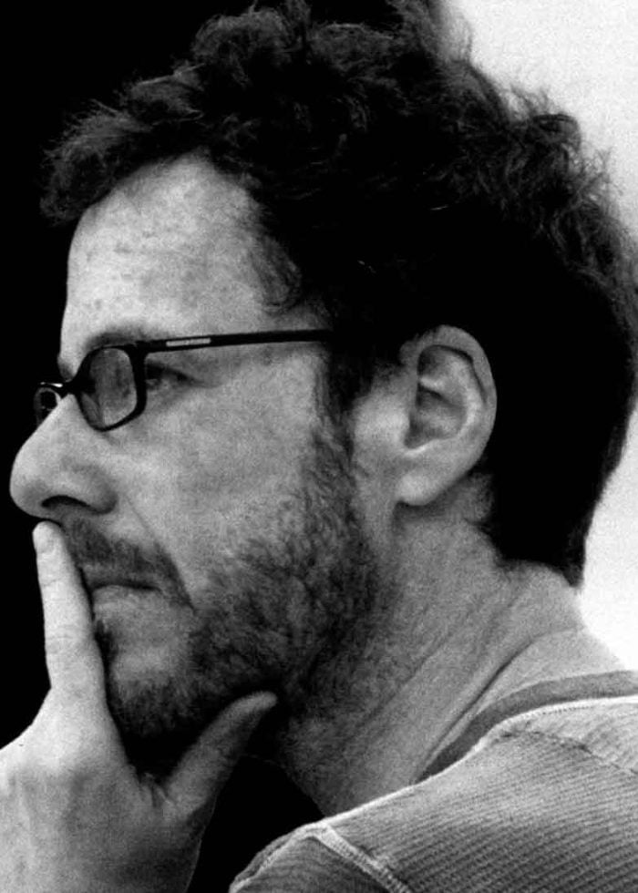 Ethan Coen in a thoughtful pose, wearing glasses and a beard.