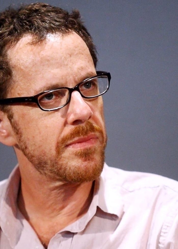 Ethan Coen wearing glasses and looking thoughtful.