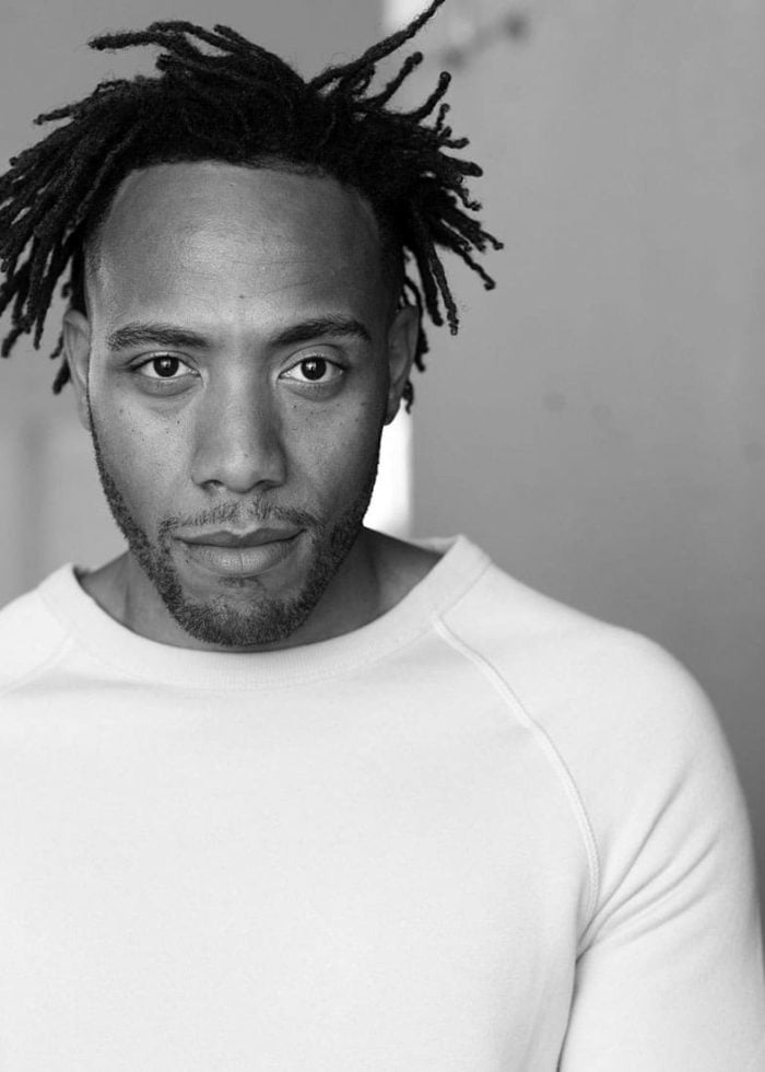 Portrait of Franck Juste with dreadlocks, looking directly at the camera