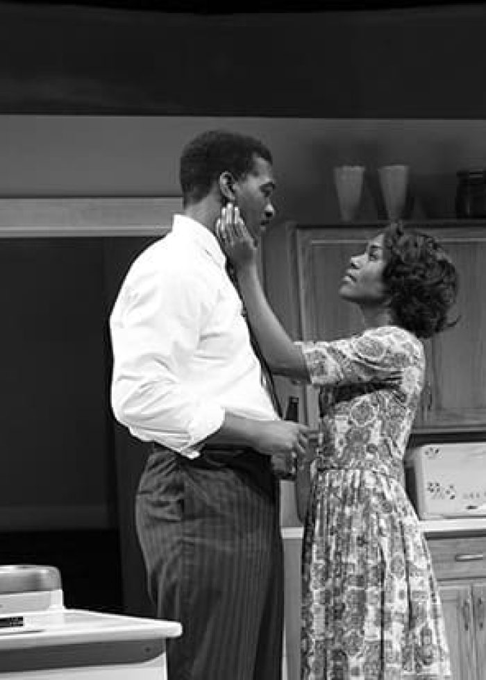 Actors in a scene from Fireflies, a play about a Black family. A woman touches a man's face in a kitchen.