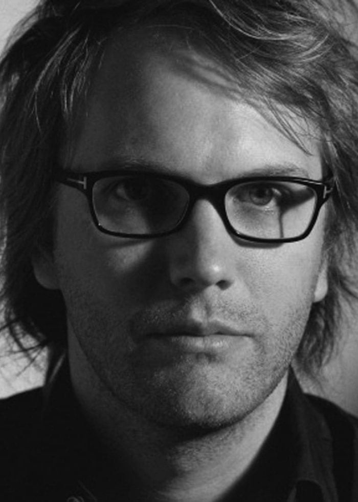 Close-up portrait of Florian Zeller wearing glasses, looking directly at the camera