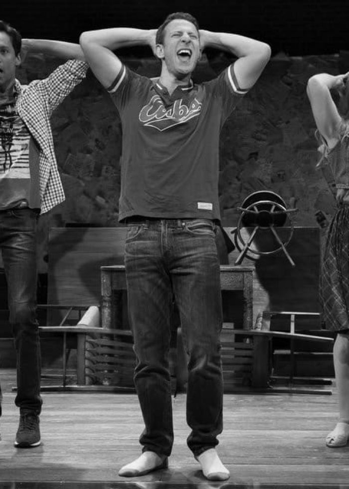 Actors on stage performing, arms raised. Discovering Stories in the Words Left Behind.