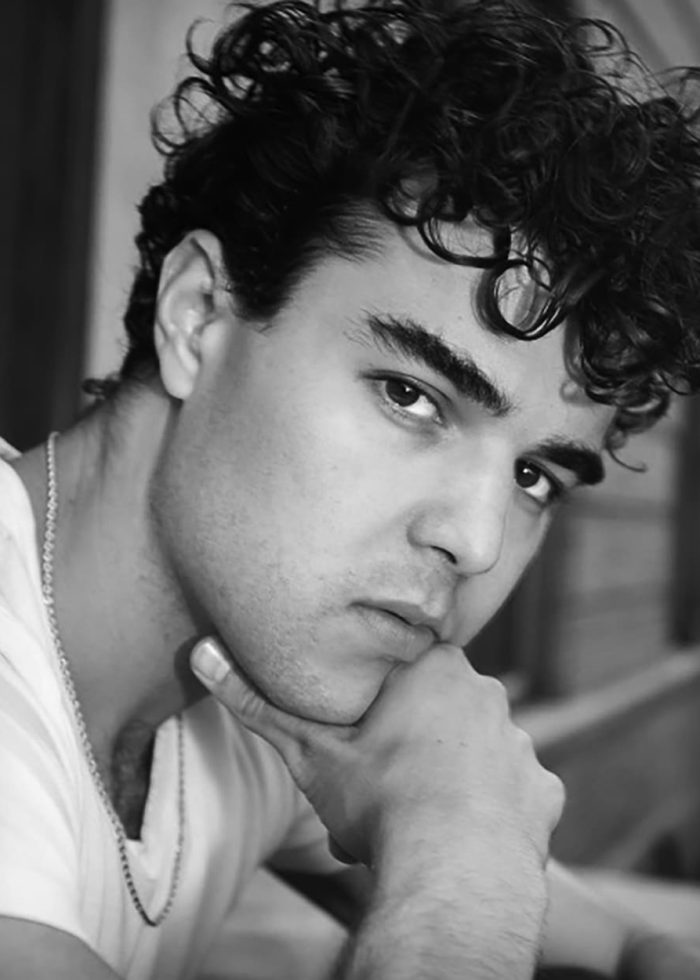 Francisco-Gonzalez-headshot-bw Close-up portrait of Francisco J. González with curly hair, resting chin on hand