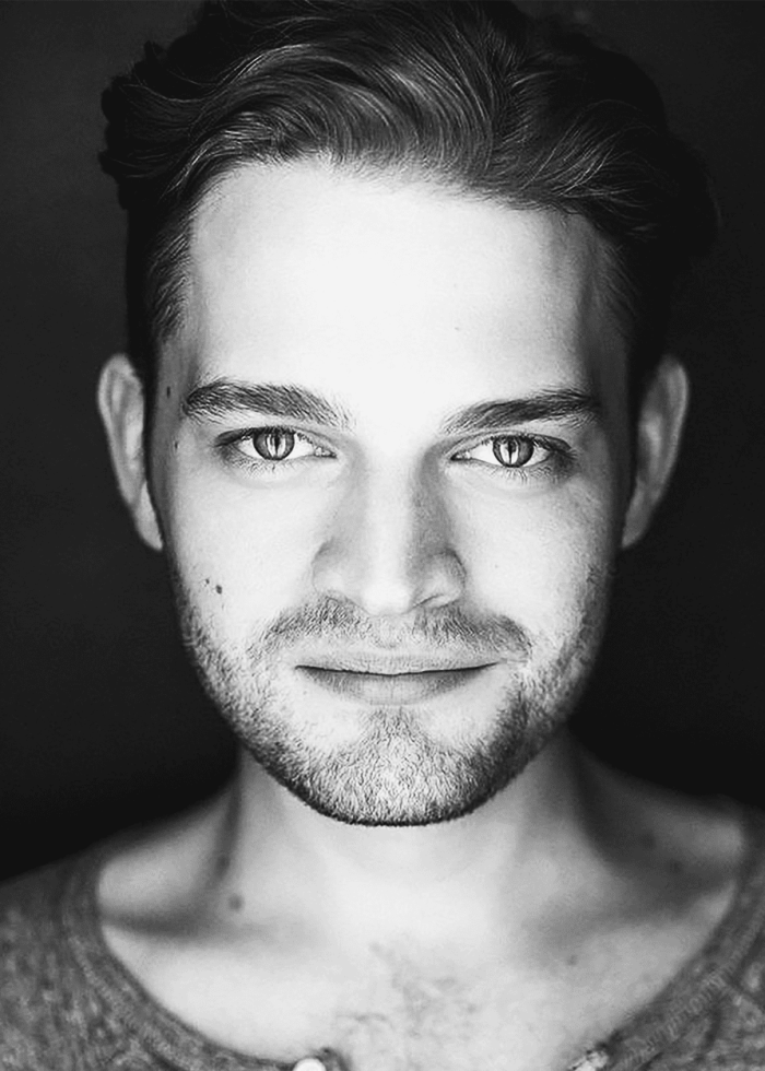 Close-up portrait of Christopher Geary, smiling, with a short beard and dark hair.
