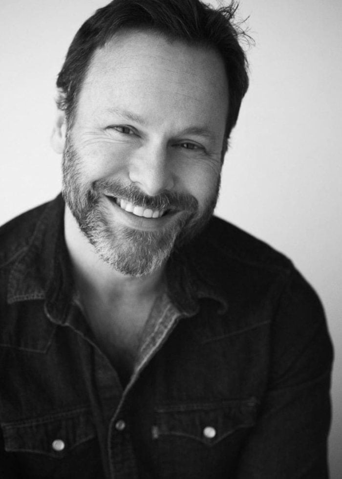 Smiling man with beard in black and white portrait.