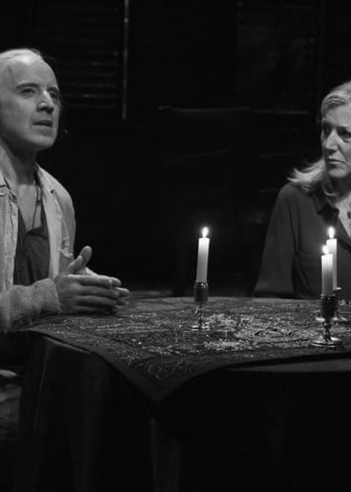Actors in a scene from Ghost Stories: The Shawl & Prairie du Chien, lit by candlelight.