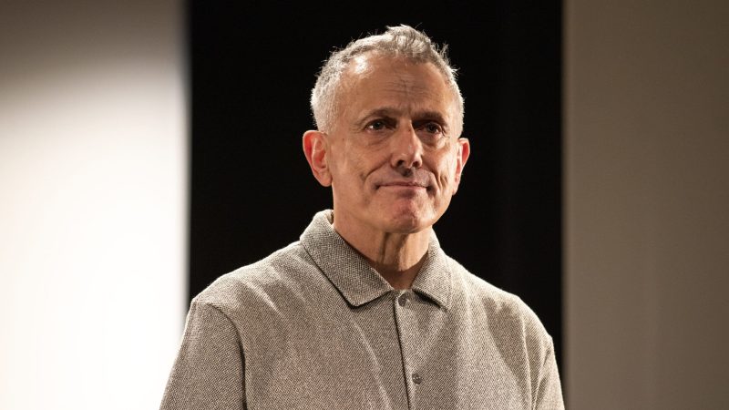 Man with gray hair and a button-down shirt looking thoughtfully