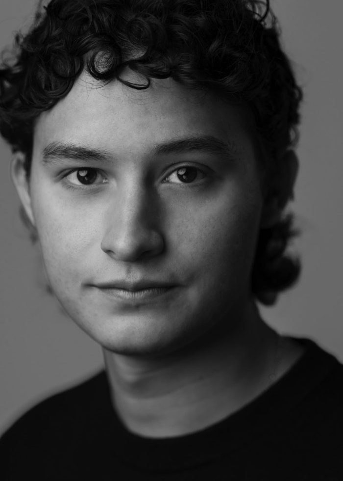 Headshot of Dominic Gross, a young man with curly hair, looking at the camera.