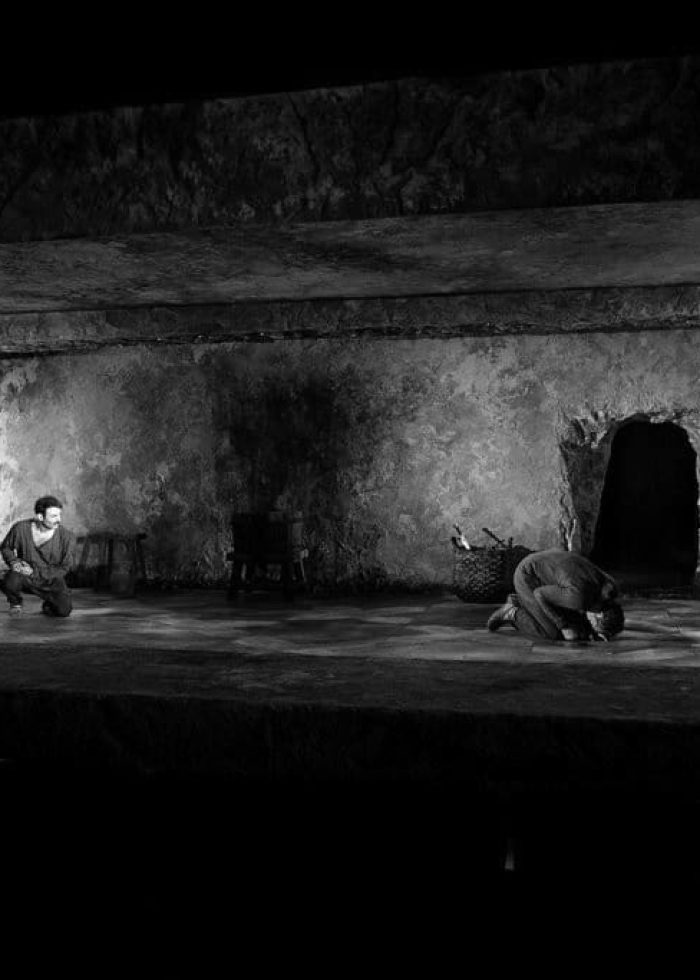 Two actors on stage in a stark, dark setting. Review of "Guards at the Taj" theatre production.