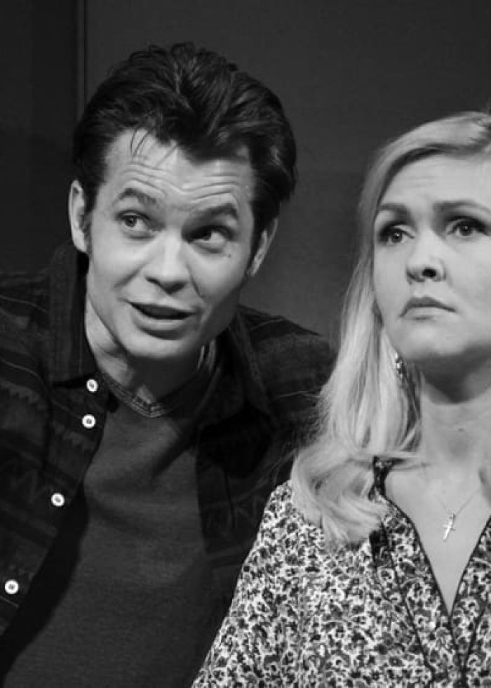 Timothy Olyphant in a scene from 'Hold on to Me Darling'. The actor gestures while looking at a woman.