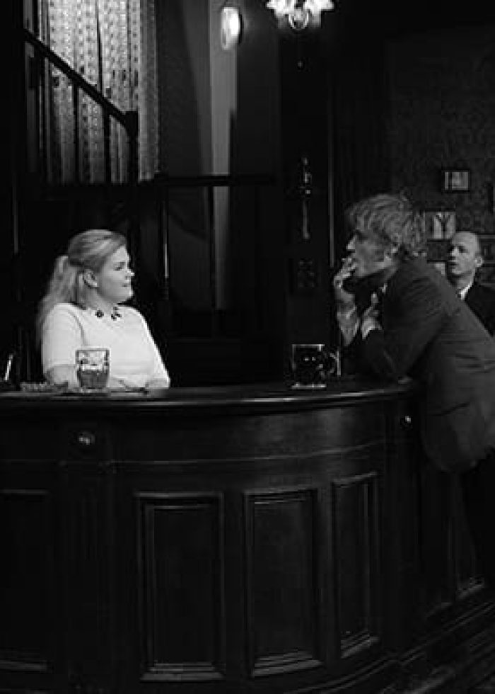 Scene from "Hangmen" play: Actors in a bar setting, black and white.