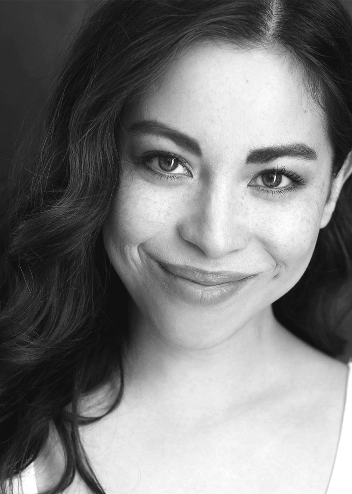 Black and white portrait of Hannah Florence smiling, with freckles and wavy hair.
