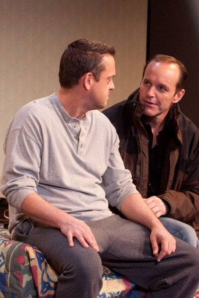 Two men in a scene from a play, sitting on a bed. Happy Hour.