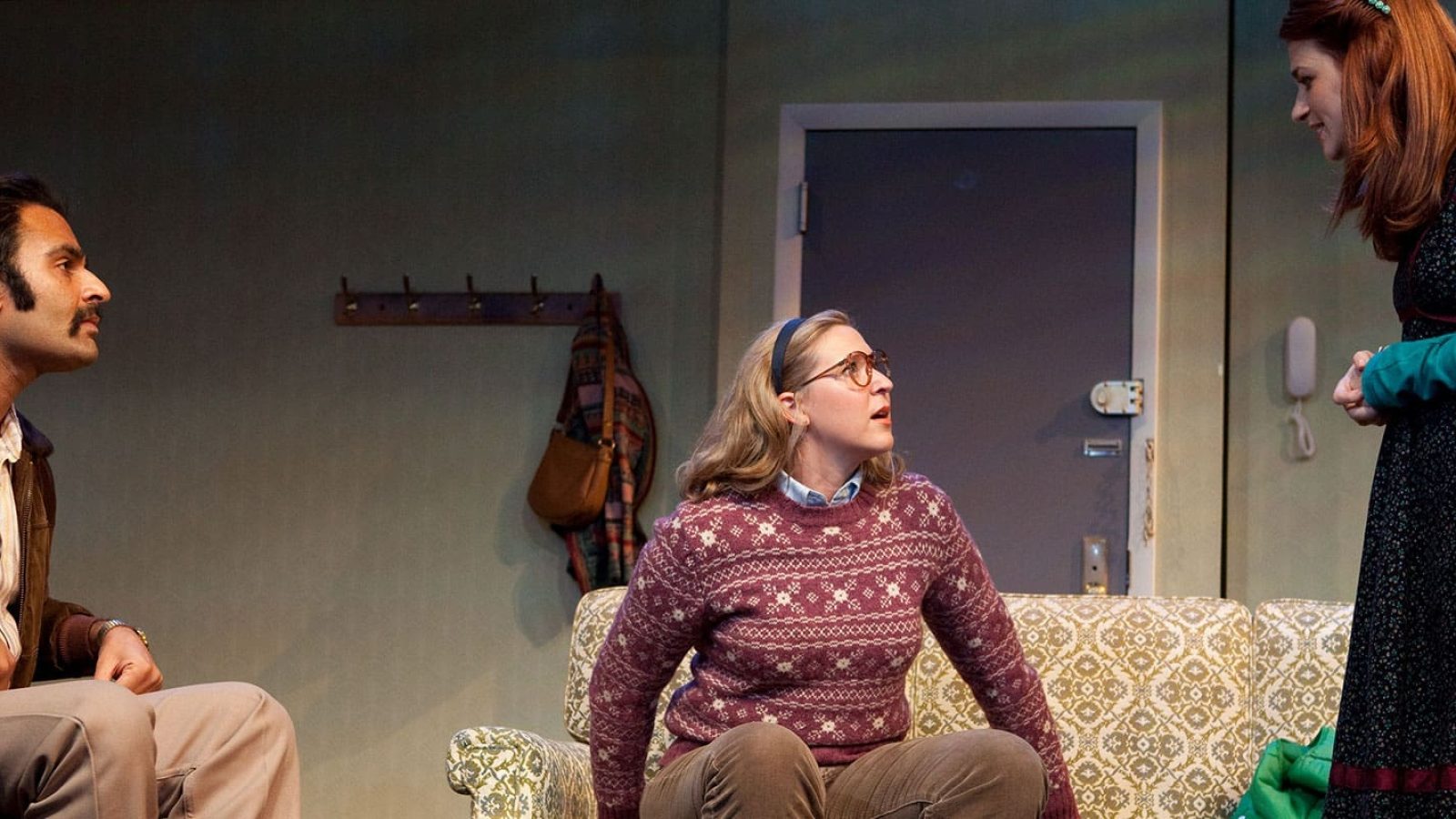 Three actors in 1970s attire during a dramatic scene.