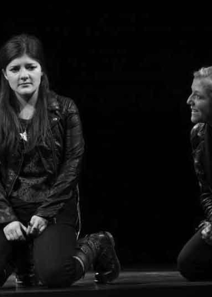 Two actresses kneeling on stage during a performance of 'Harper Regan'