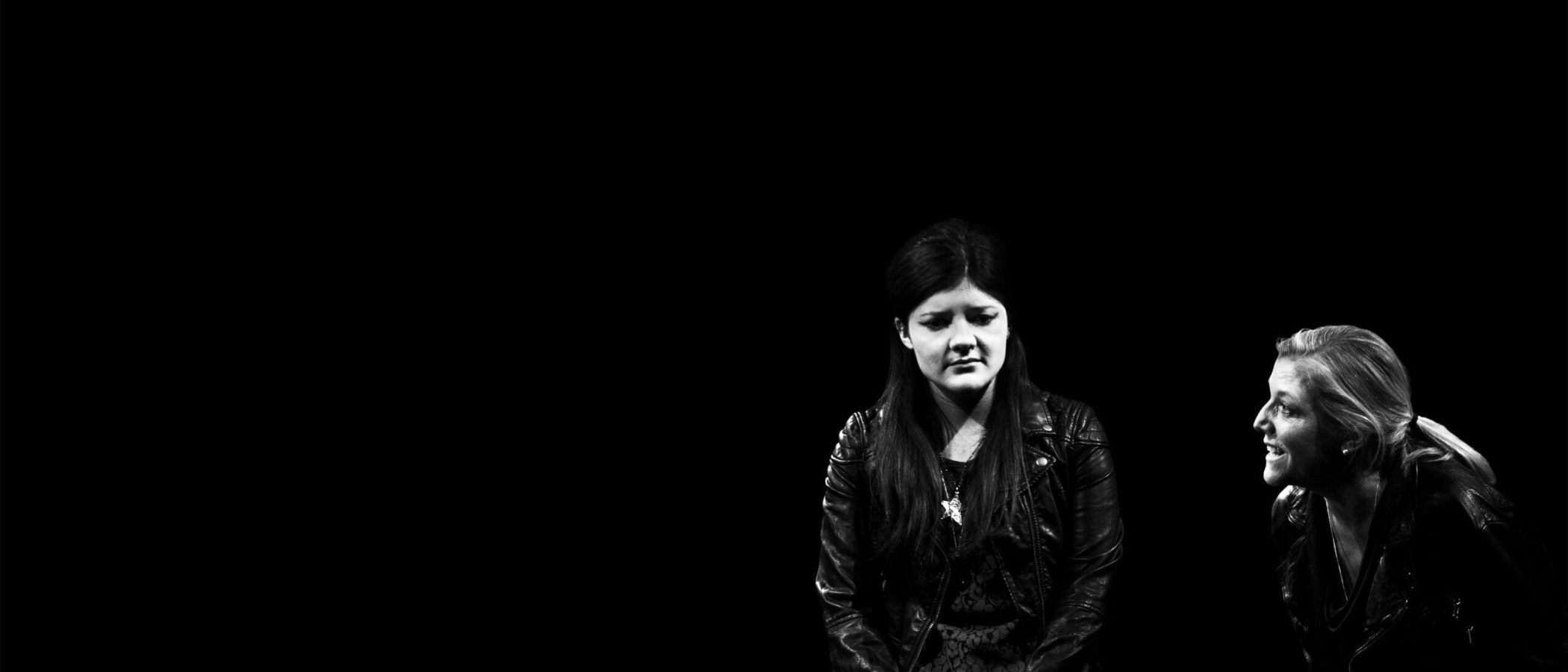 Two women in leather jackets, one looking down, the other looking up. Harper Regan.