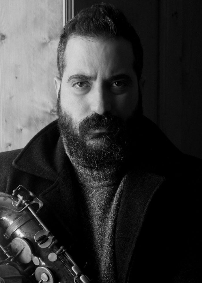 Hery Paz holding a saxophone, black and white portrait.