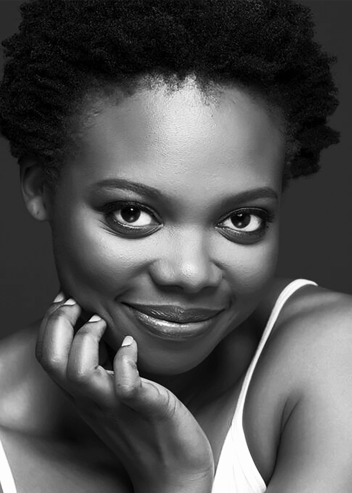 Susan Heyward, smiling portrait in black and white, resting hand on chin.