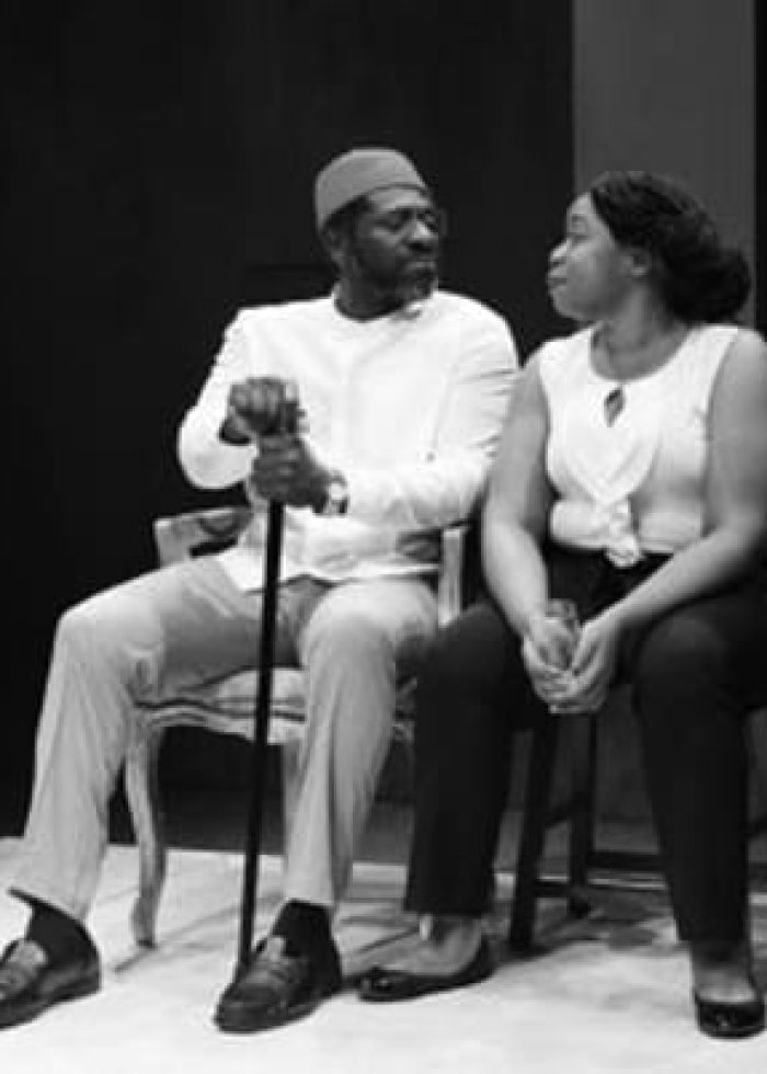 Man and woman seated, looking at each other. Black and white image.