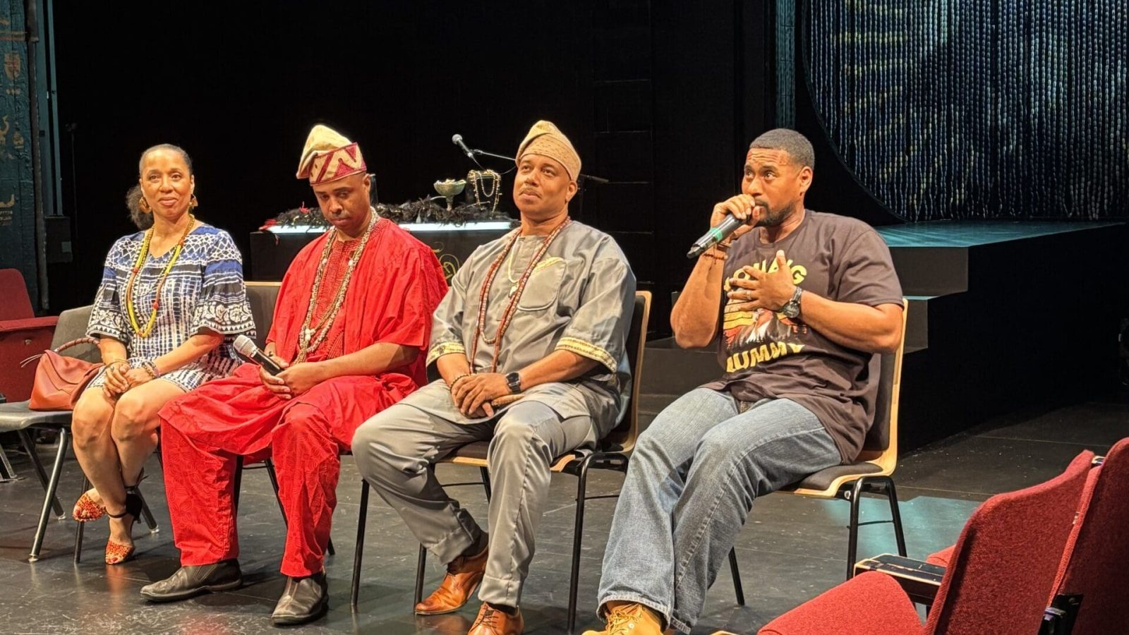 Panel discussion featuring speakers in traditional African attire on a stage.